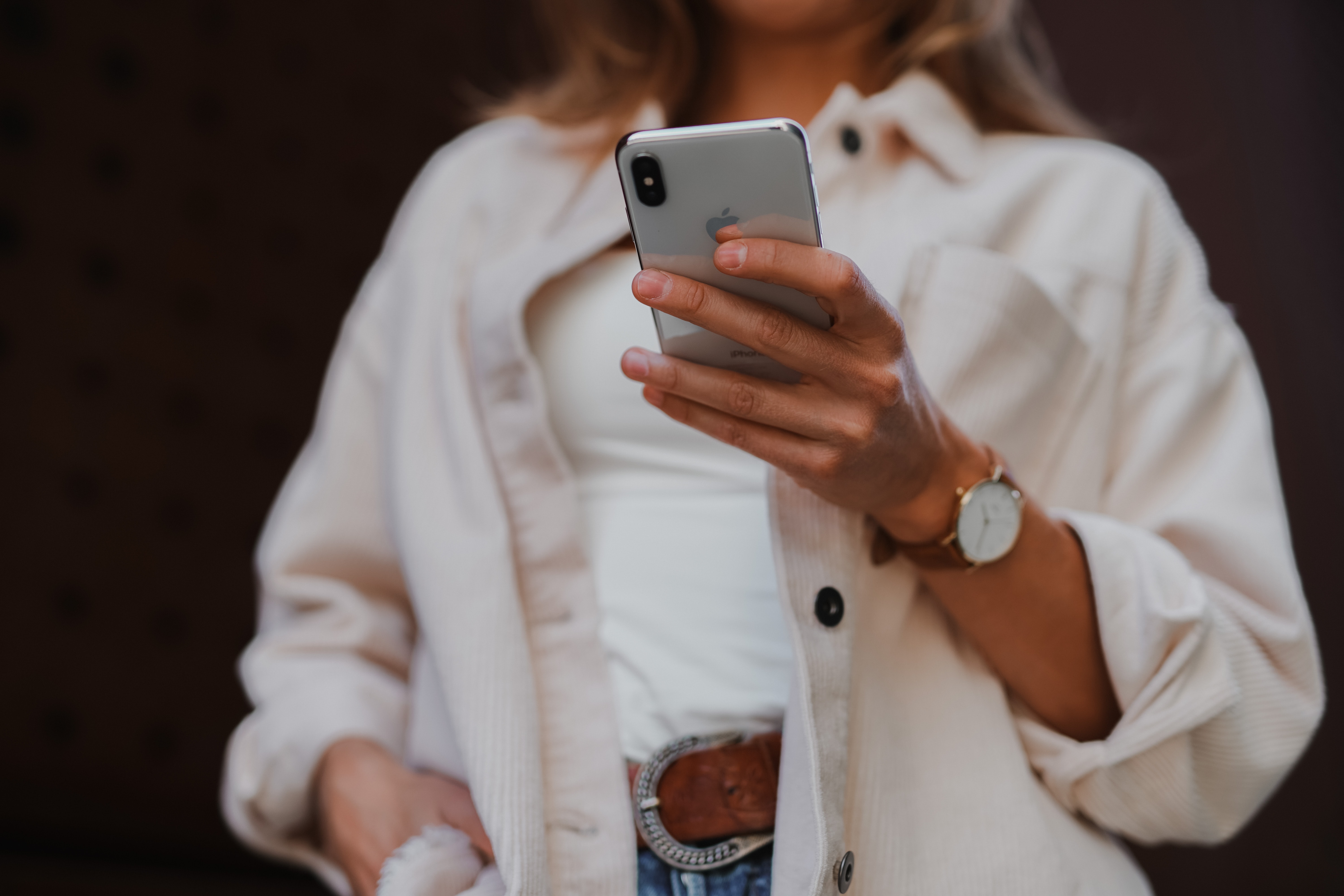 Image of lady in white shirt holding a mobile phone using an app